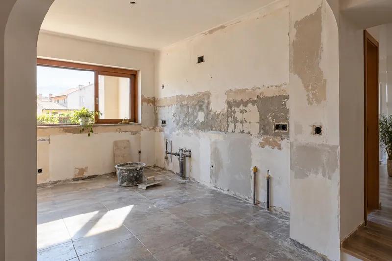 Visualización conceptual IA: Cocina sin muebles con paredes en preparación y zonas de enlucido.